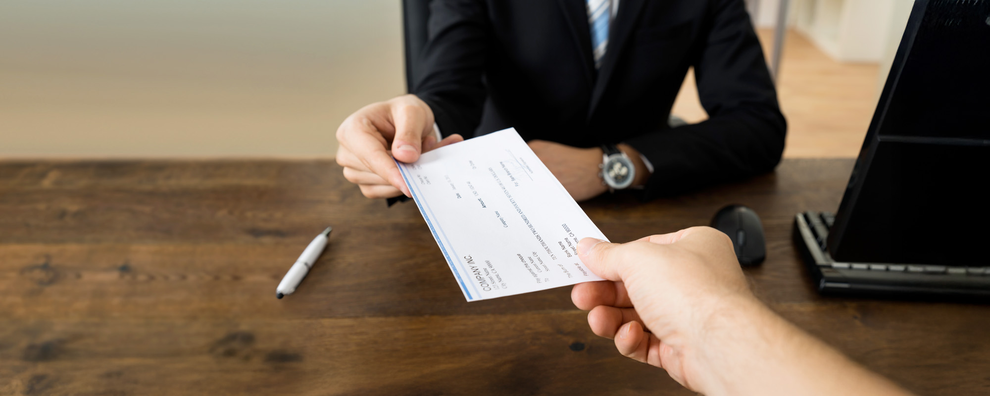 Businessman Hands Giving Cheque To Other Person In Office